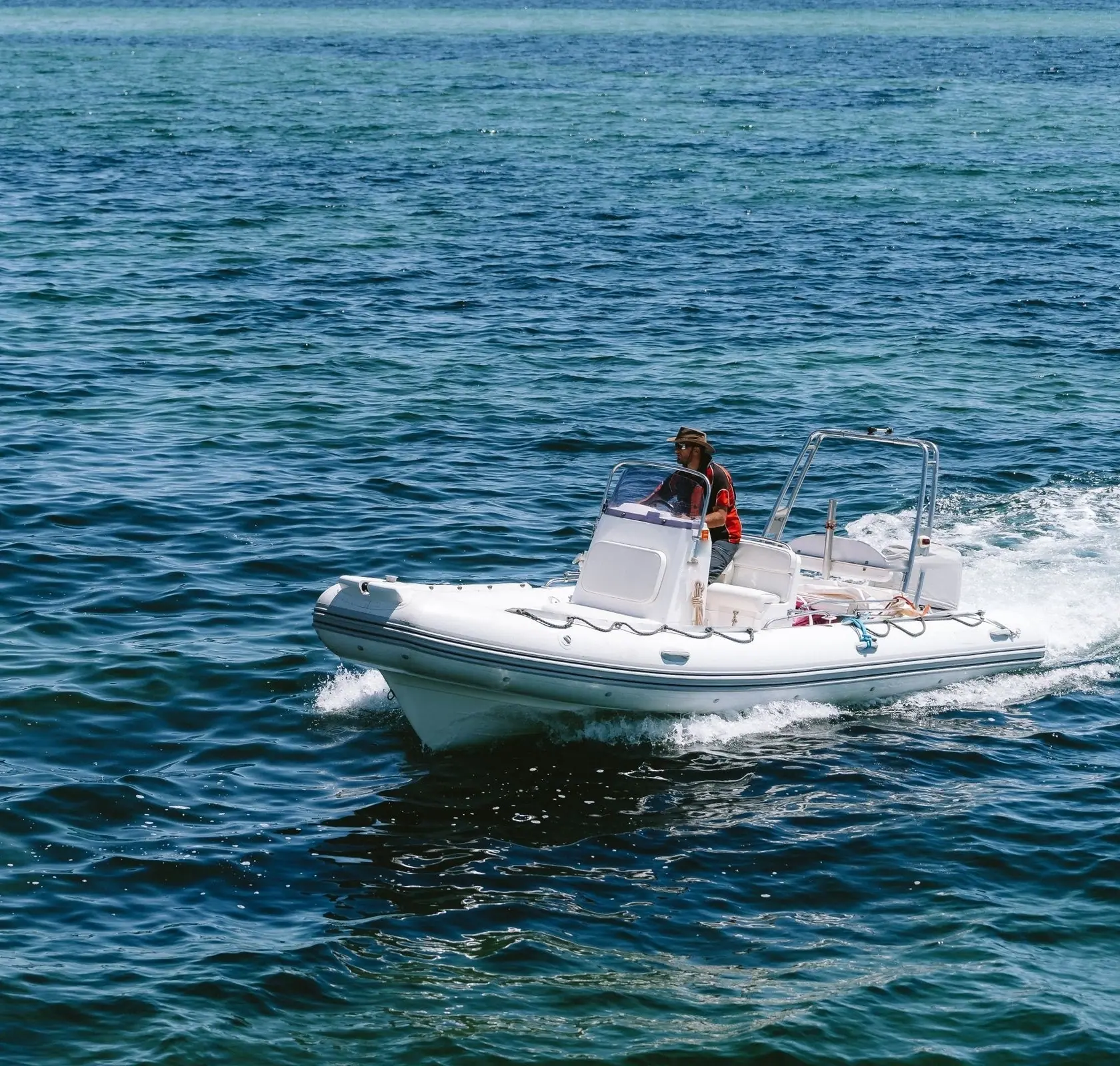 Semi-rigide blanc de 60 CV en route, le pilote debout à la console