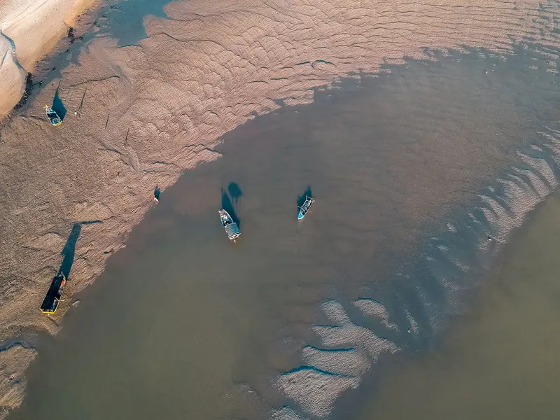Vue du ciel d'un estran de vase à marée basse, deux barques posées