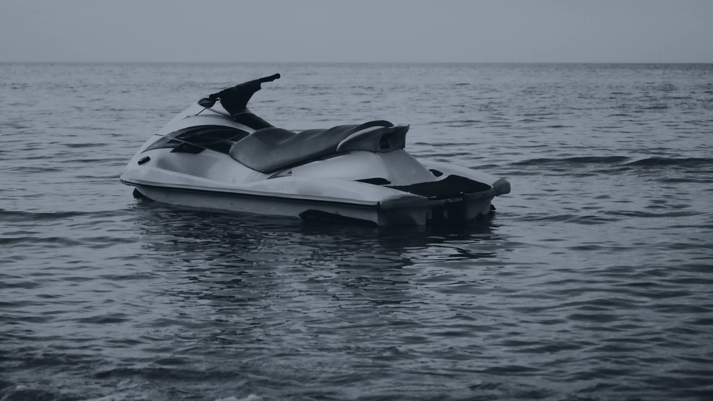 Un jet-ski vide au mouillage, sur une mer presque plate, à la nuit tombante