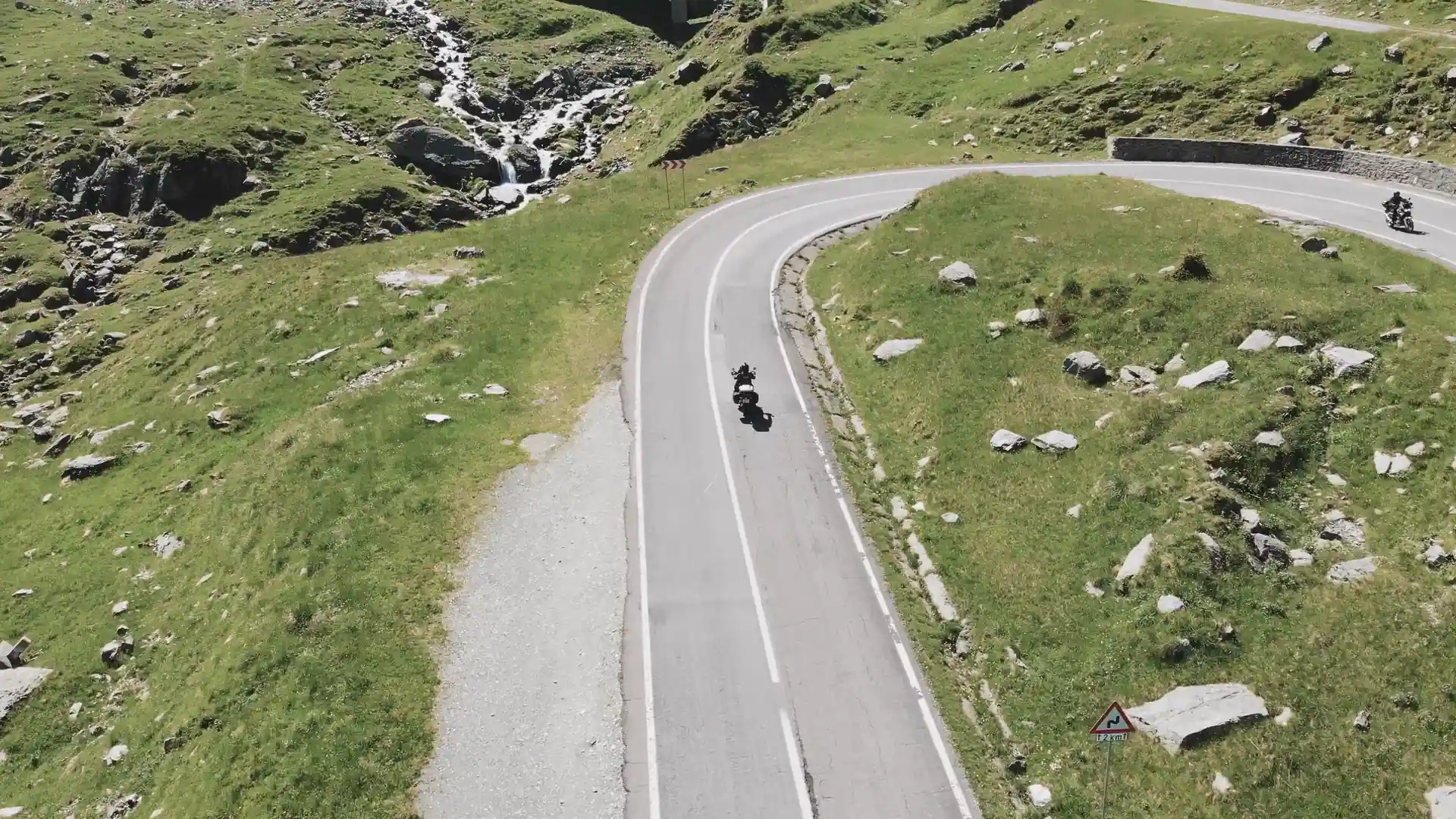 Deux motos de tourisme dans les épingles d’un col, vues du ciel