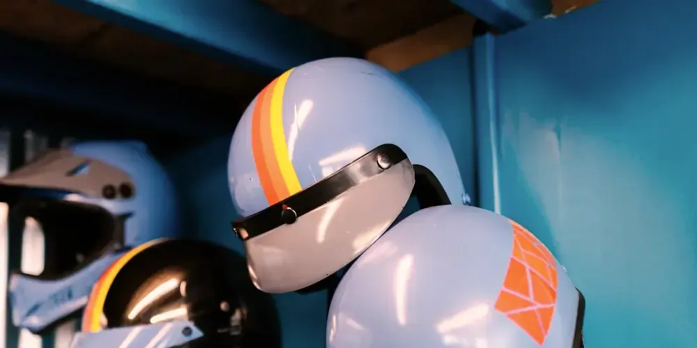 Casques jet bleu ciel à bandes orange, accrochés à un mur bleu