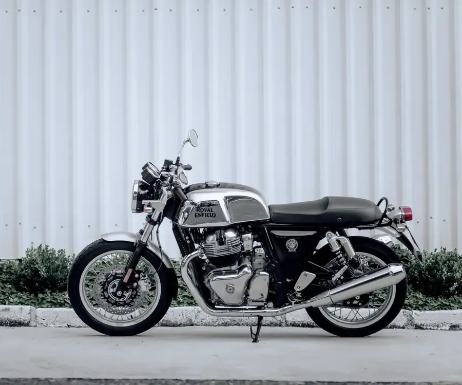 Royal Enfield Continental GT 650 de profil, réservoir chromé, devant un mur de tôle blanche