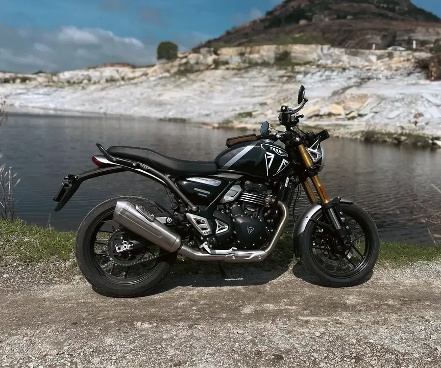 Triumph Speed 400 noire de profil, fourche dorée, au bord d’un plan d’eau