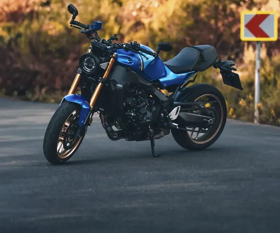 Yamaha XSR900 bleue, fourche et jantes dorées, arrêtée à l’entrée d’un virage