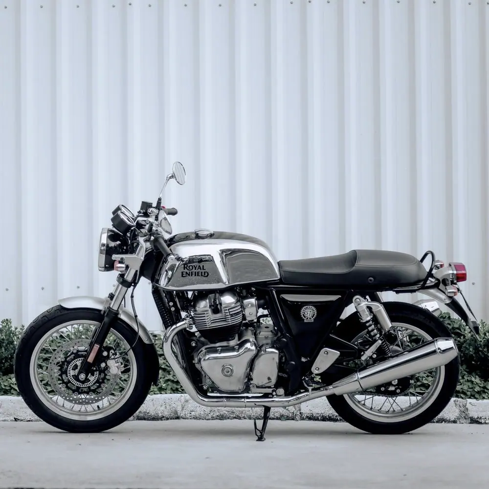 Royal Enfield Continental GT 650 de profil, réservoir chromé, devant une tôle blanche