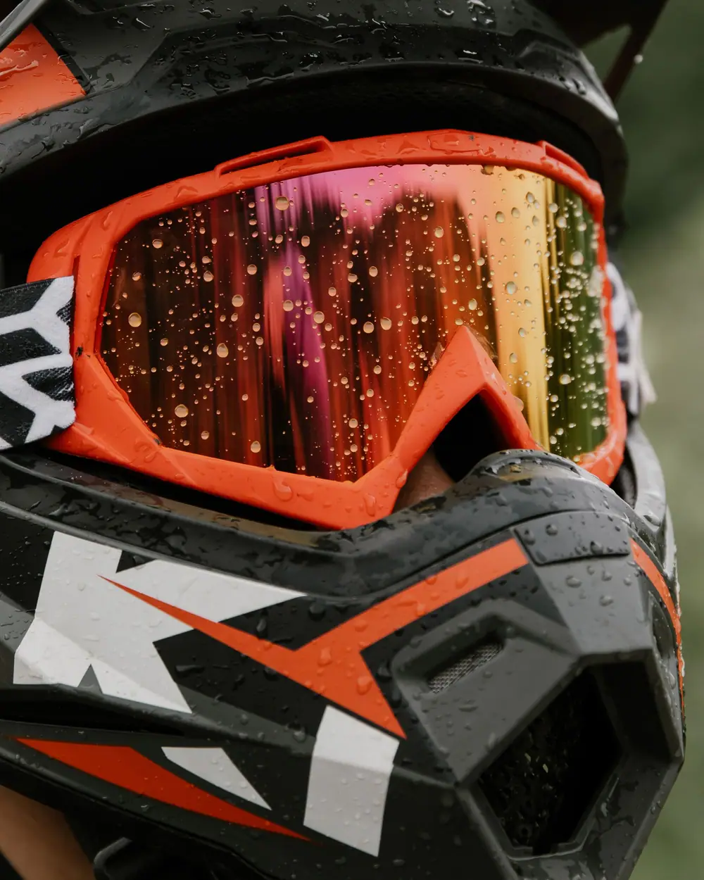 Casque tout-terrain noir et orange avec masque, couvert de gouttes de pluie