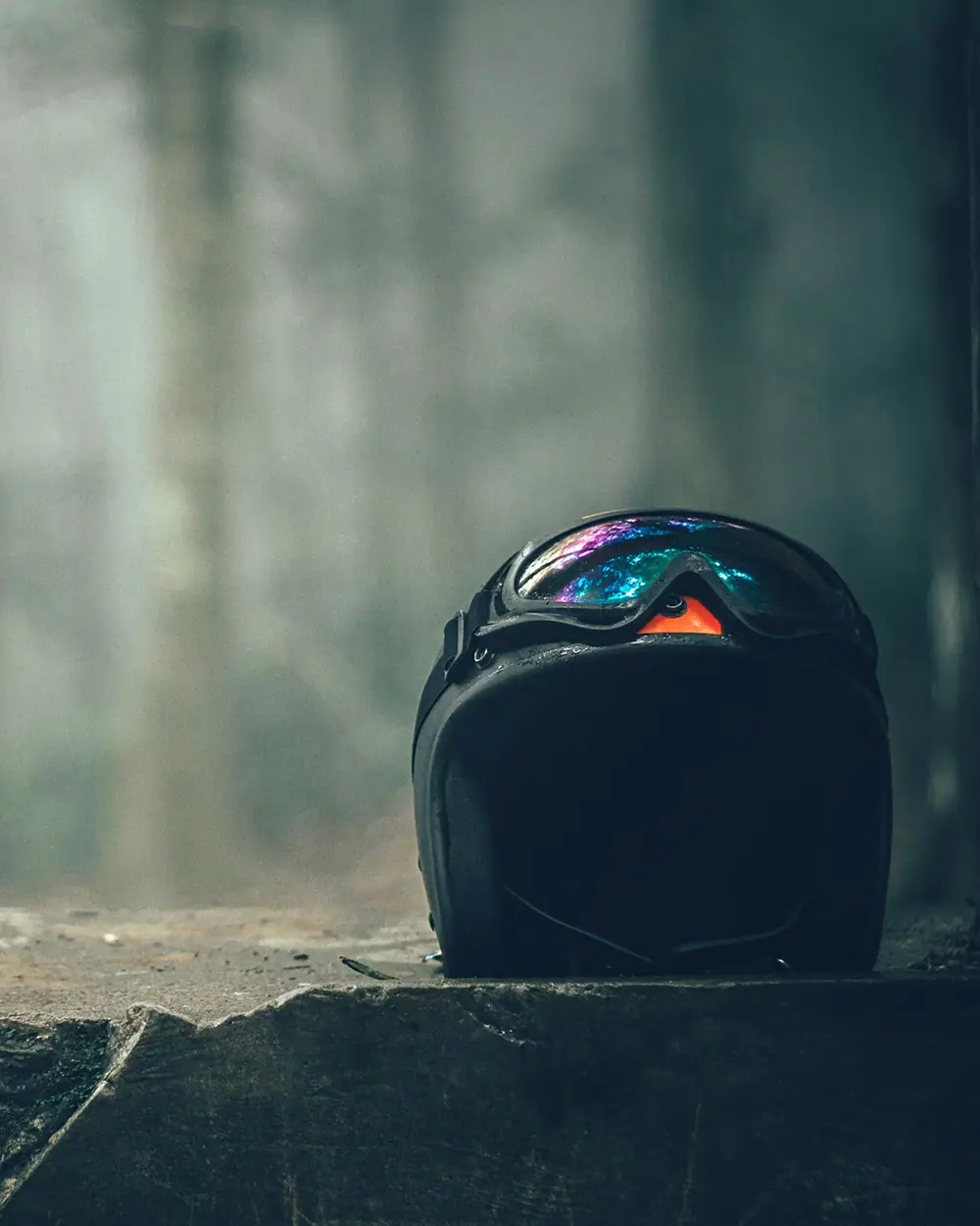 Casque et masque posés sur un muret de pierre, sous-bois dans la brume