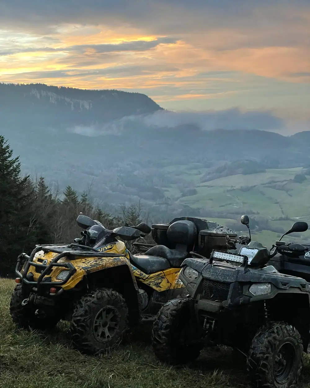 Deux quads garés sur un belvédère herbeux, vallée dans la brume